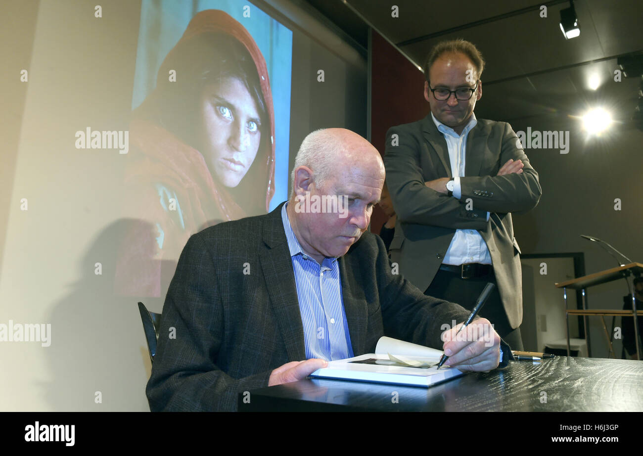 Munich, Allemagne. 28 Oct, 2016. Steve McCurry, photographe nous signe ses livres après son 'événement sur la lecture. Une passion sans frontières' dans la Literaturhaus à Munich, Allemagne, 28 octobre 2016. Dans l'arrière-plan sur l'écran est l'un de ses plus célèbres photos d'une fille afghane, qui a été la couverture de National Geographic. Photo : FELIX/HOERHAGER dpa - PAS DE FIL - SERVICE/dpa/Alamy Live News Banque D'Images