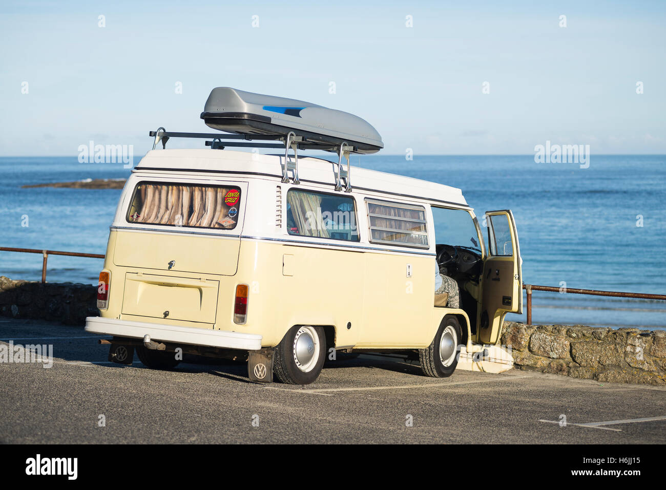 Une Volkswagen Bulli bus vintage camping à Sennen Cove parking plage donnant sur la mer bleue dans le soleil du matin en été, Cornwall, UK Banque D'Images