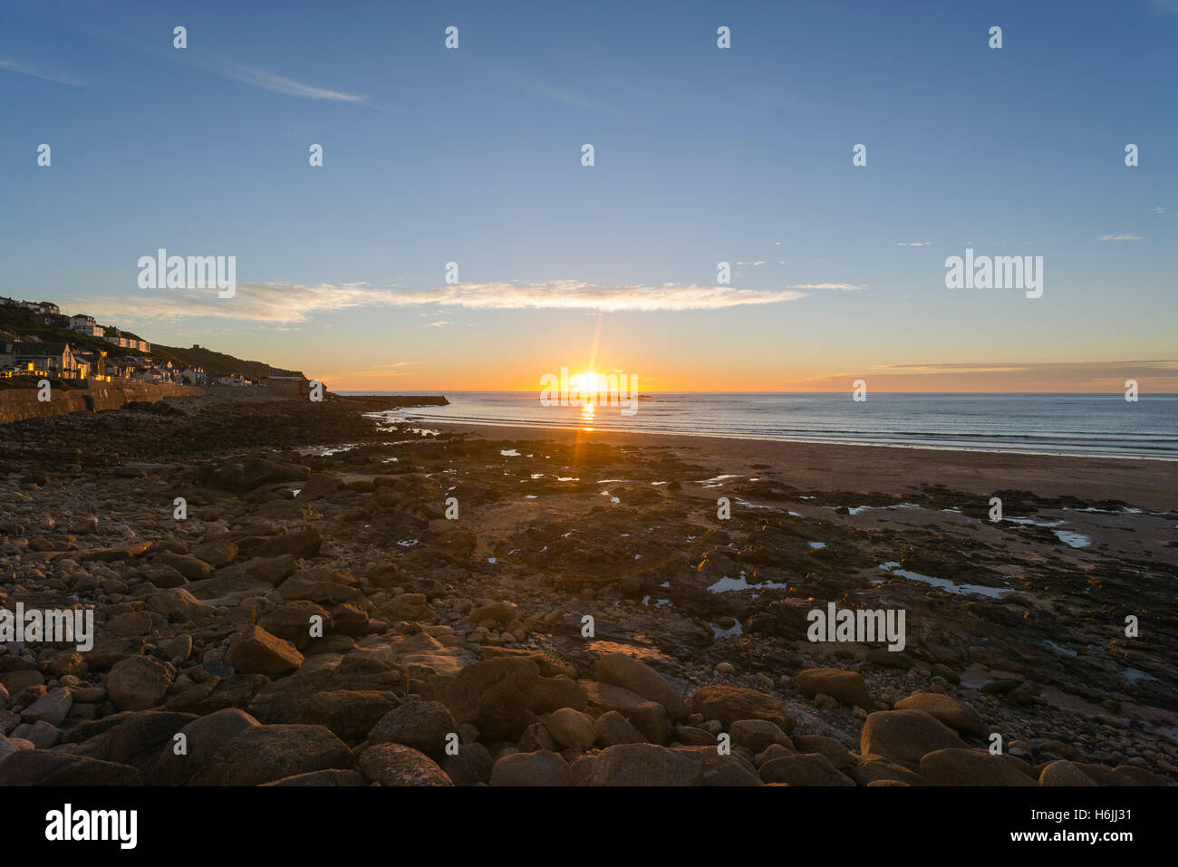 Au coucher du soleil de l'océan atlantique et la plage de galets à Sennen Cove à marée basse près de Land's End en été, côte ouest de Cornwall, England, UK Banque D'Images
