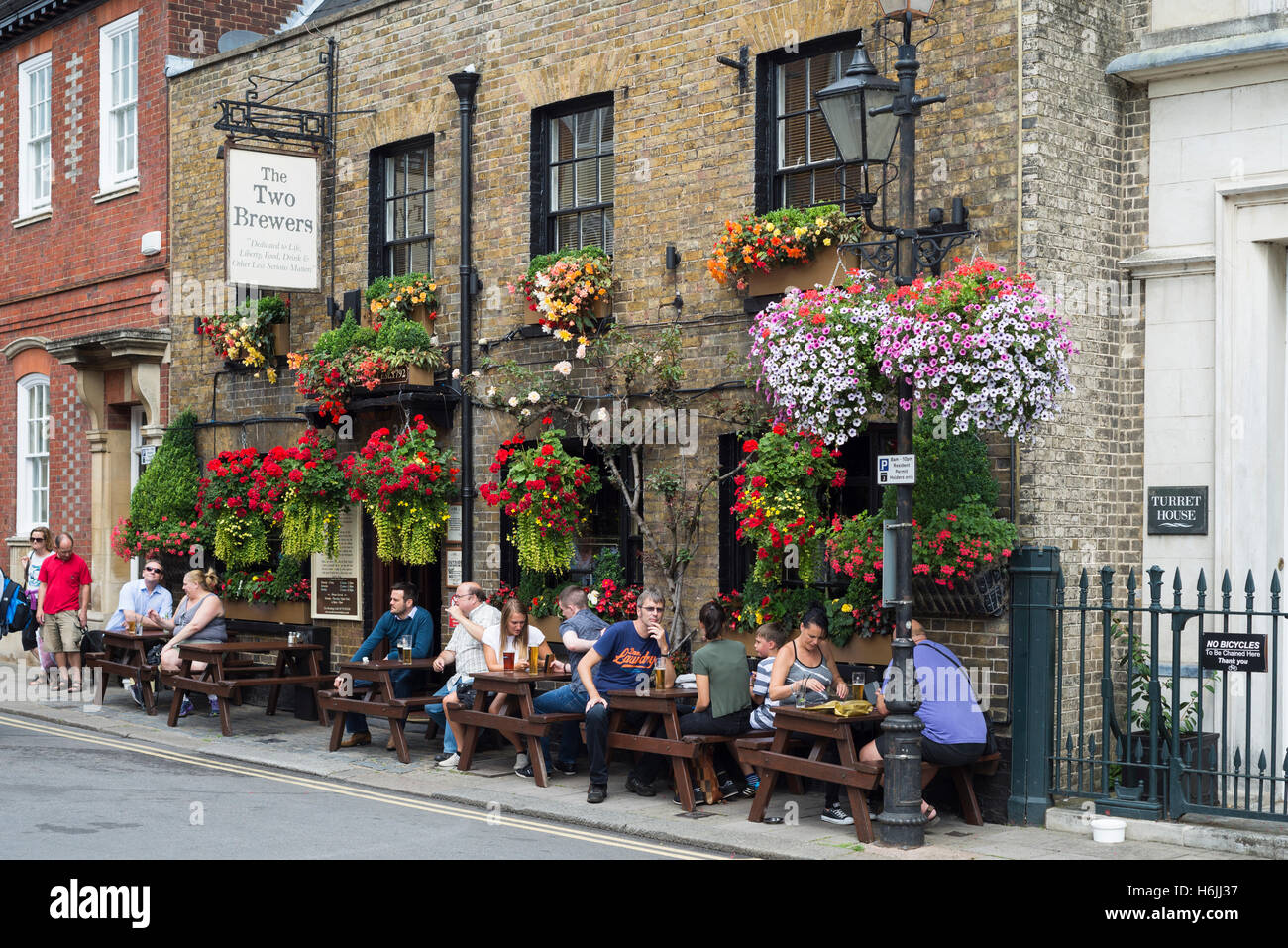 Des gens assis et de boire en dehors des locaux de l'deux brasseries pub décoré de fleurs en fleurs près de Windsor castle un jour d'été, UK Banque D'Images