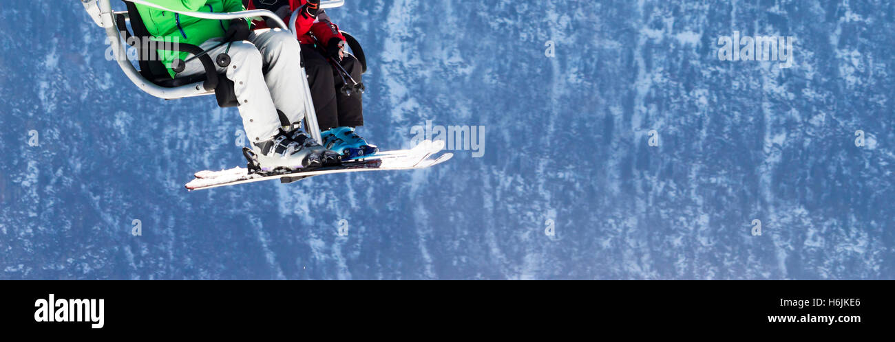 Skieurs sur télésiège avec les montagnes enneigées en arrière-plan Banque D'Images