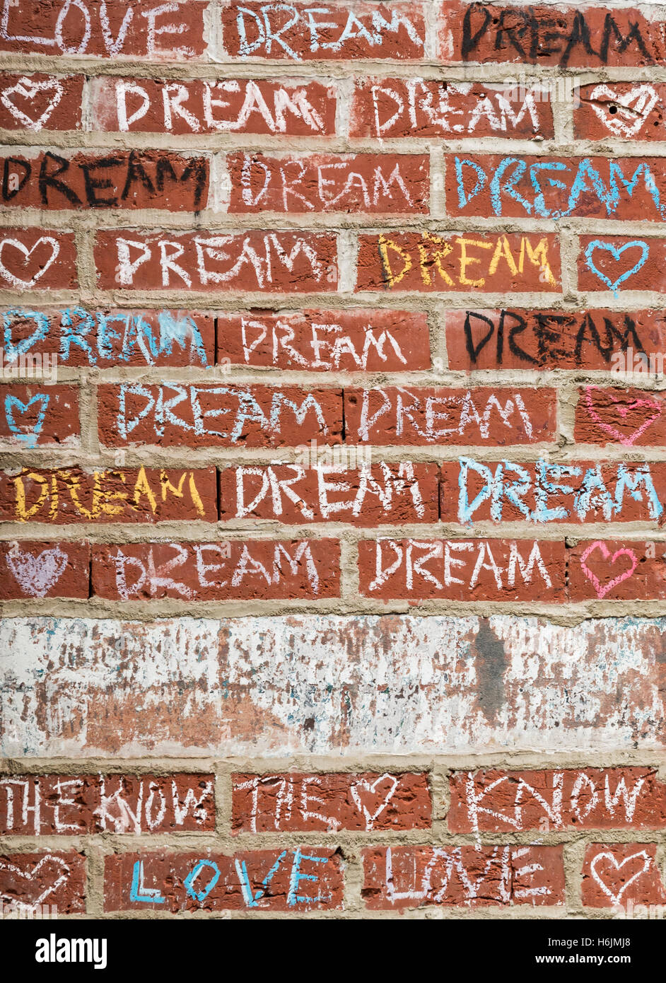 Craie de couleur graffiti sur un mur de brique rouge avec les mots d'amour, rêve, et le savoir sur l'extérieur d'un magasin. Banque D'Images