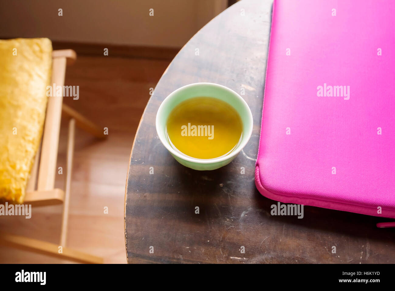 Le thé vert et l'Apple Mac Book Air dans le cas rose sur la table ronde Banque D'Images