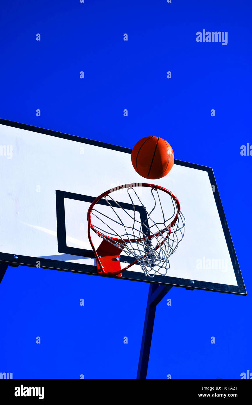 Le basket-ball. Balle est l'atterrissage au panier. Ciel bleu clair sur l'arrière-plan. Banque D'Images