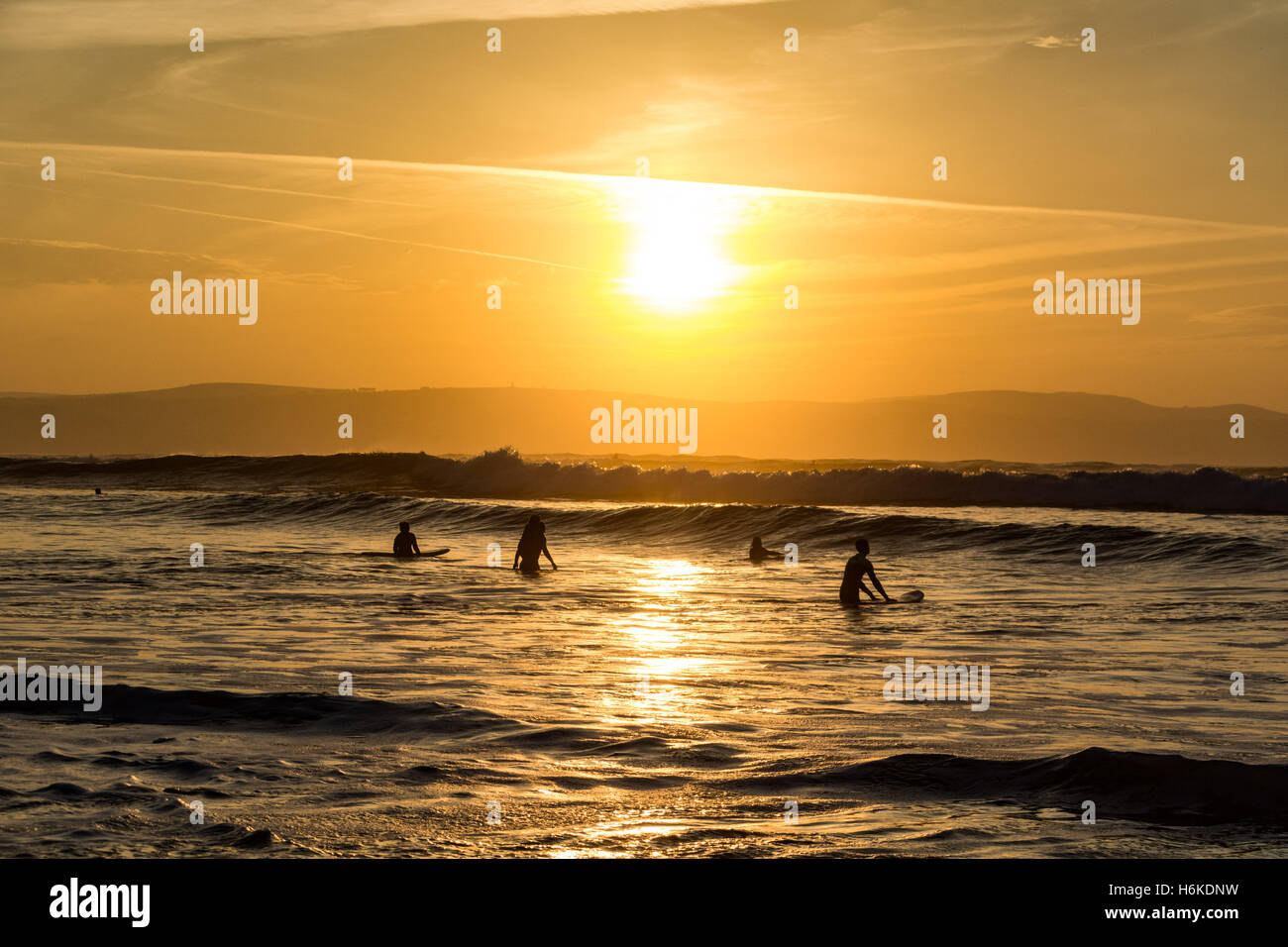Gwithian, Cornwall, UK. 30e Cotober 2016. Météo britannique. Au coucher du soleil avec des températures de 17 degrés C, les surfeurs et promeneurs de chiens profiter de la mer au coucher du soleil. Crédit : Simon Maycock/Alamy Live News Banque D'Images