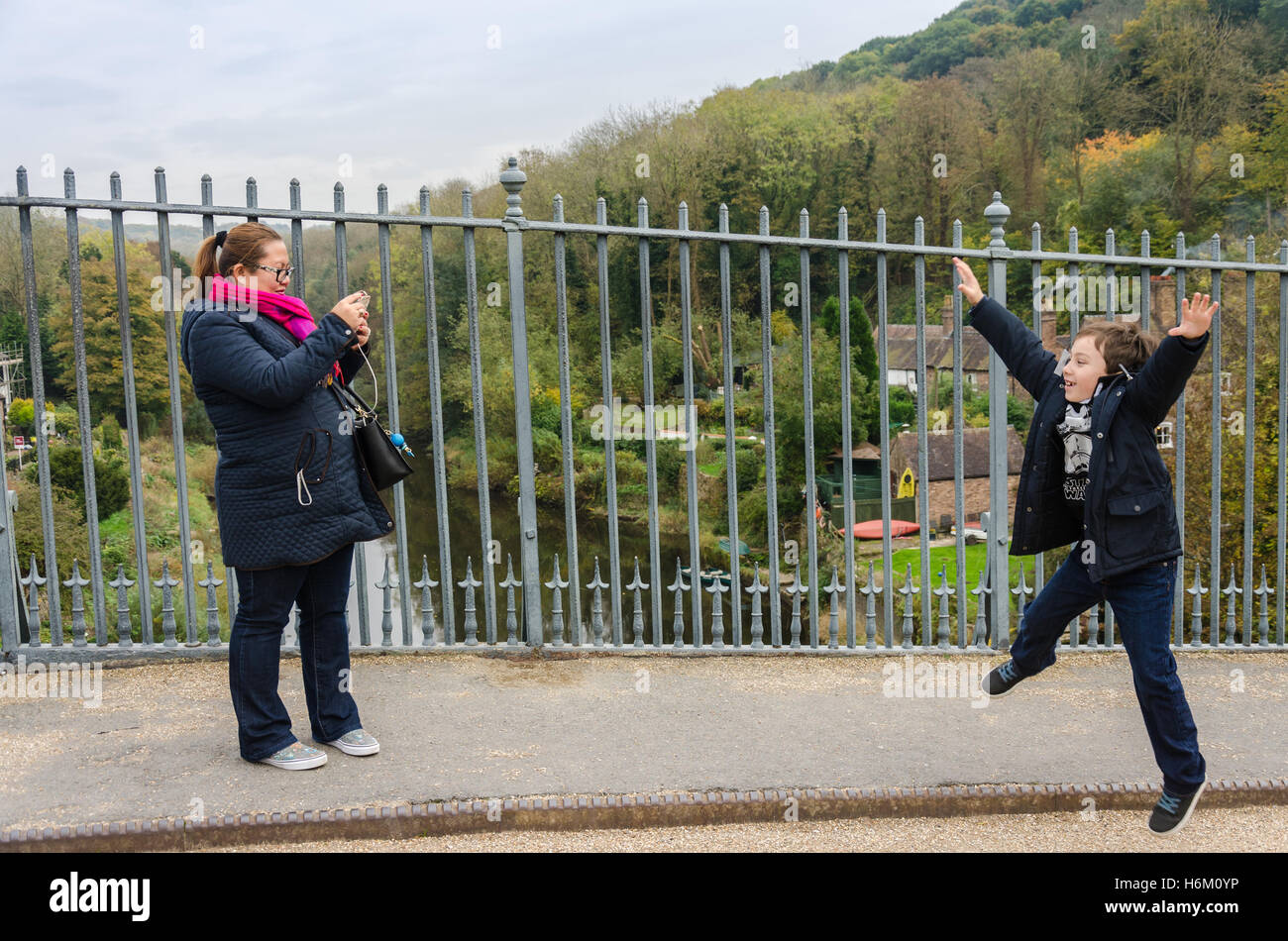 Une maman prend une photo de son fils faisant un saut star tandis que dehors sur une sortie en famille. Banque D'Images