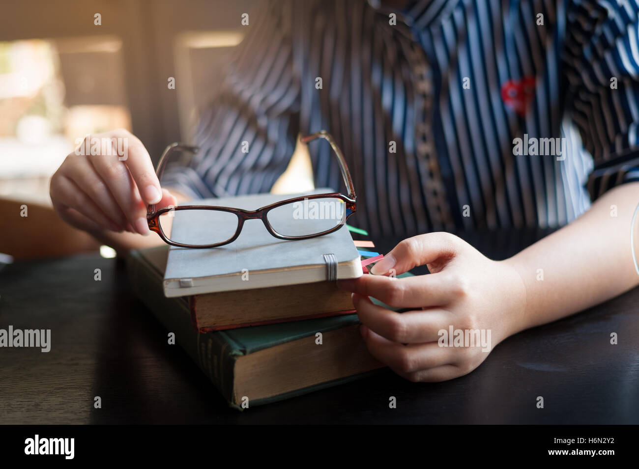 Scène de vie matin de jeunes hipster femme mettre ses lunettes sur le bas de la pile de livres dans le café. L'activité de fin de semaine ou de hobby concept Banque D'Images