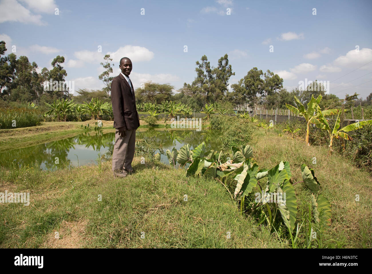 African man standing by pond dans la zone humide Longonot Horticulture Ltd Kenya Naivasha Banque D'Images