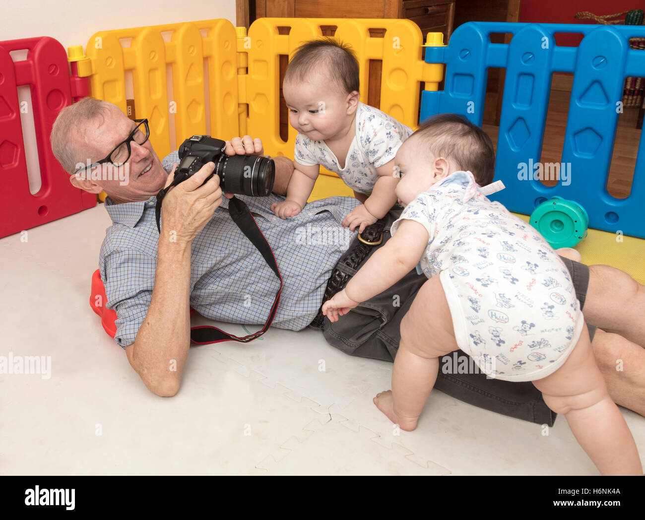 Grand-père essayant de photographier les bébés jumeaux Banque D'Images