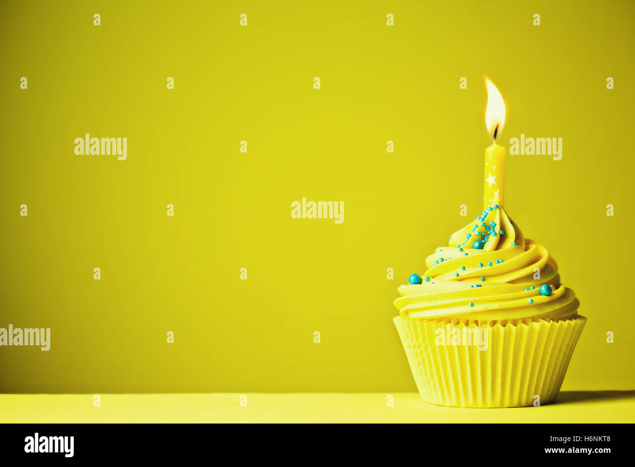 Cupcake décoré d'une seule bougie jaune Banque D'Images