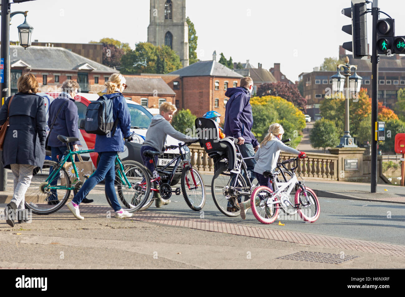 Une famille de décider de pousser leur vélo à travers une ville animée road, Worcester, Worcestershire, Angleterre, Royaume-Uni Banque D'Images