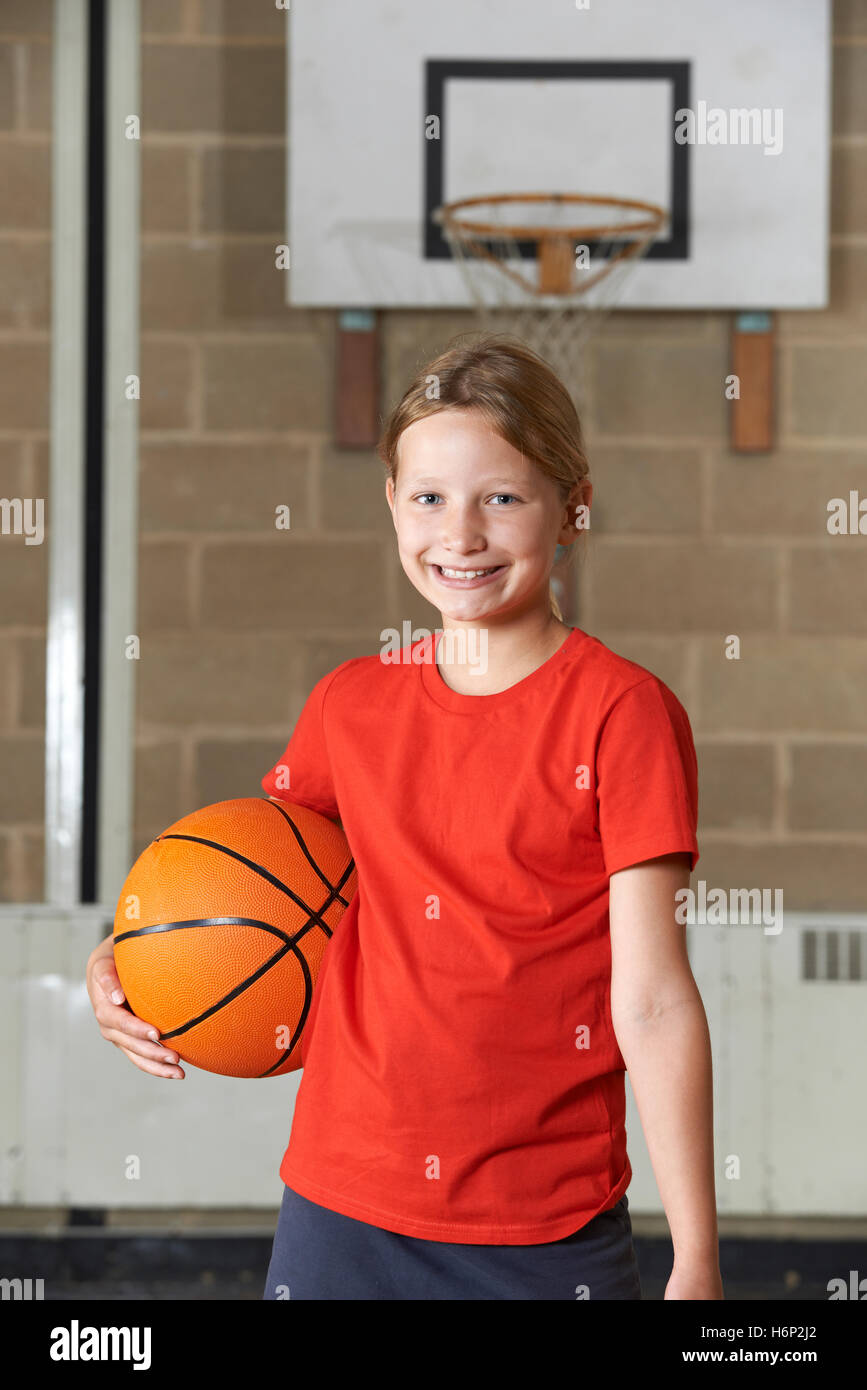 Portrait of Girl Holding Basket-ball au gymnase de l'école Banque D'Images