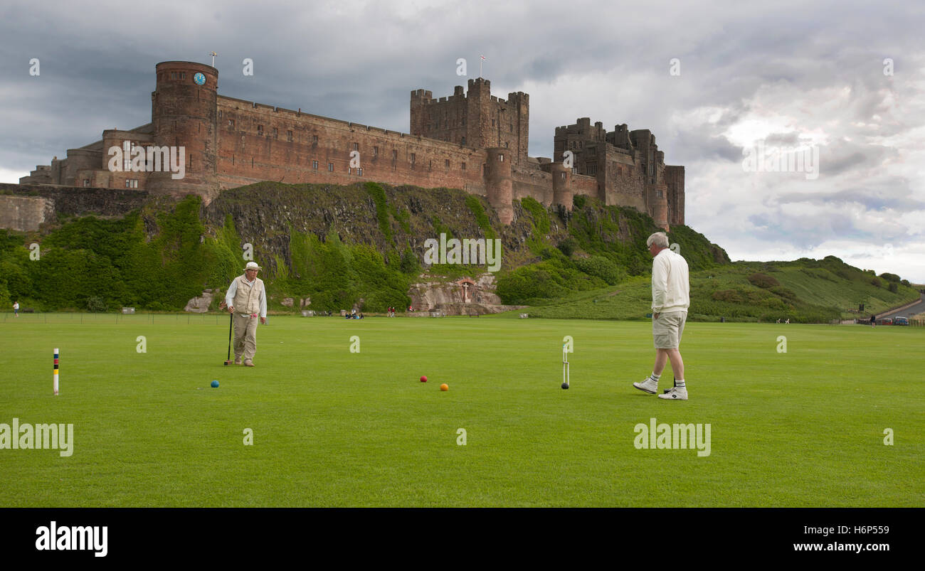 Jouer au croquet dans l'ombre de Château de Bamburgh, Bamburgh, Northumberland, England, UK. Banque D'Images