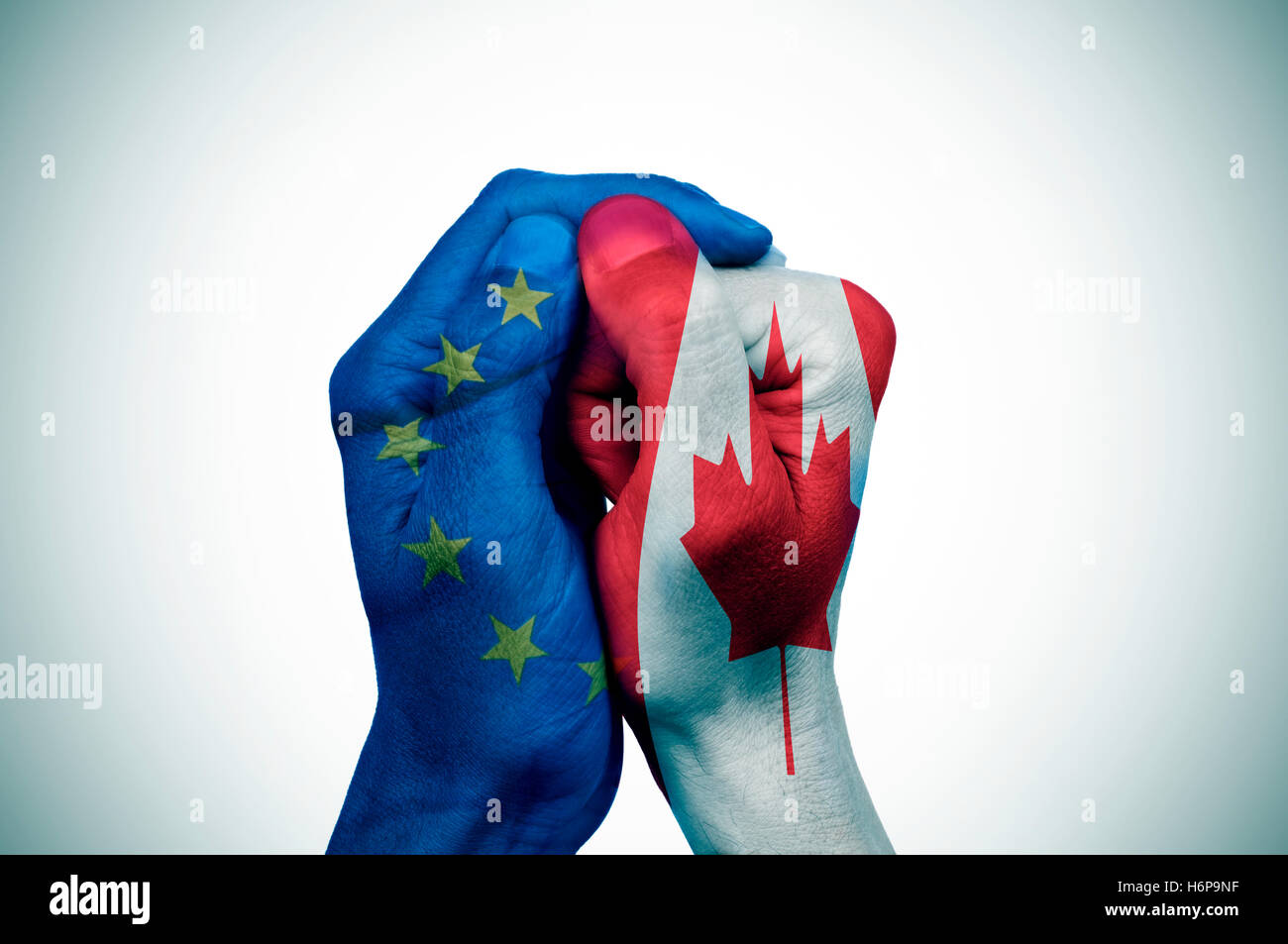 Une main, avec le drapeau de la Communauté européenne couvre une autre main à motifs de pavillon du Canada Banque D'Images