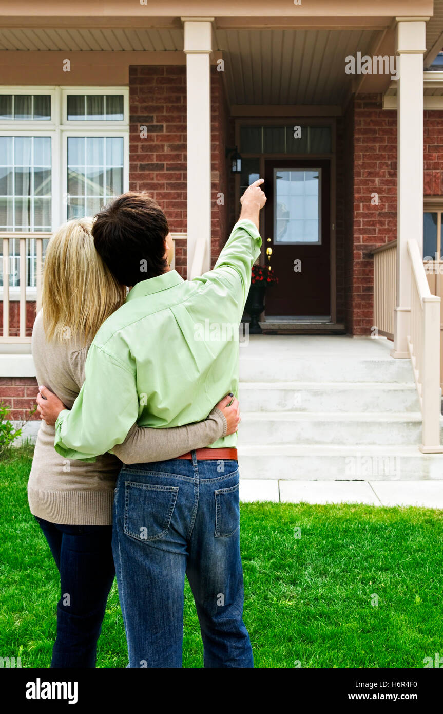Jetant un coup d'oeil construction voir voir à oeil regardant shopping hugging young couple plus jeune femme accueil pointage paire Banque D'Images
