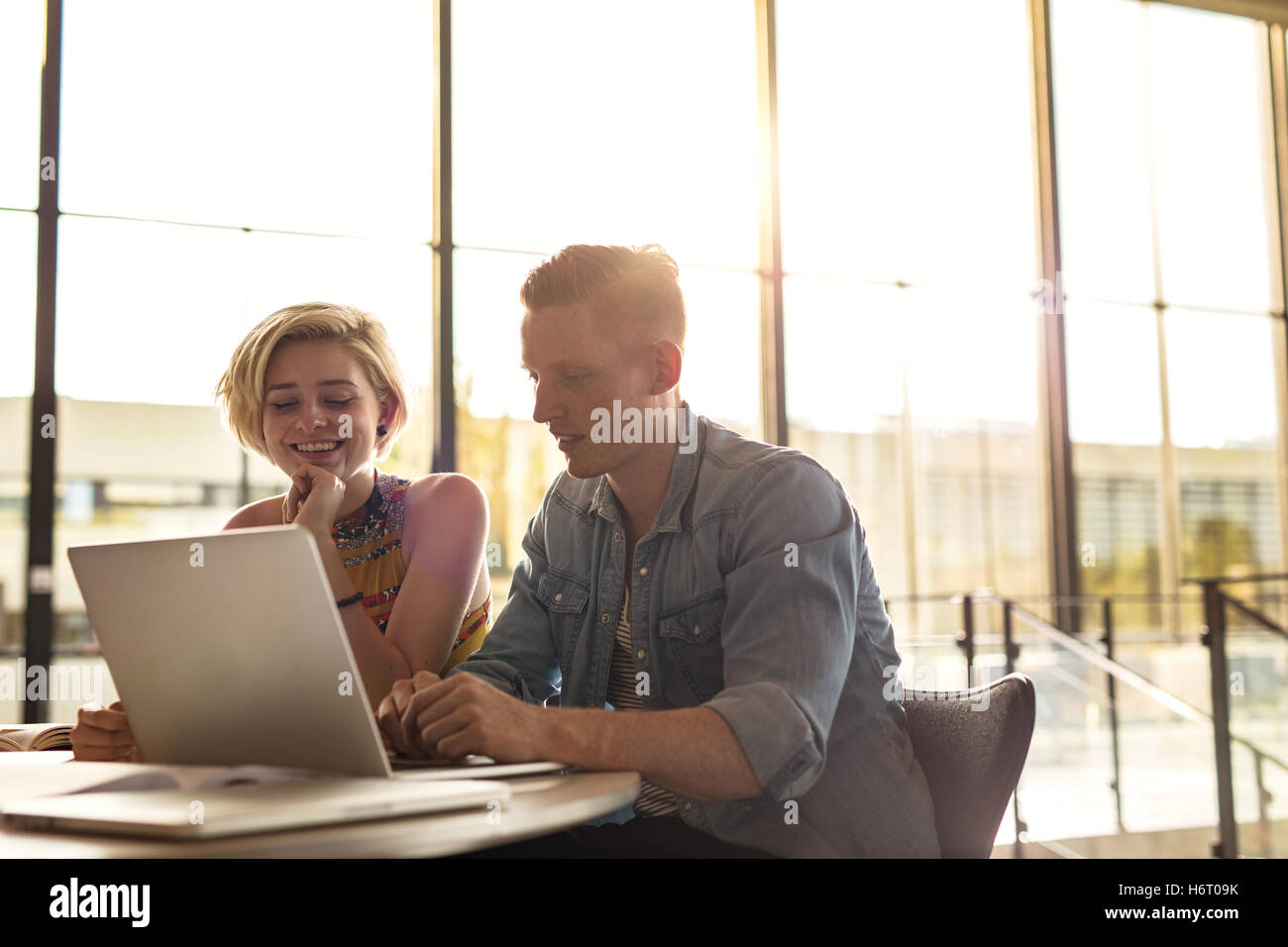 Deux jeunes étudiants universitaires qui étudient en bibliothèque. L'homme et la femme assise à la table avec un ordinateur portable. Banque D'Images