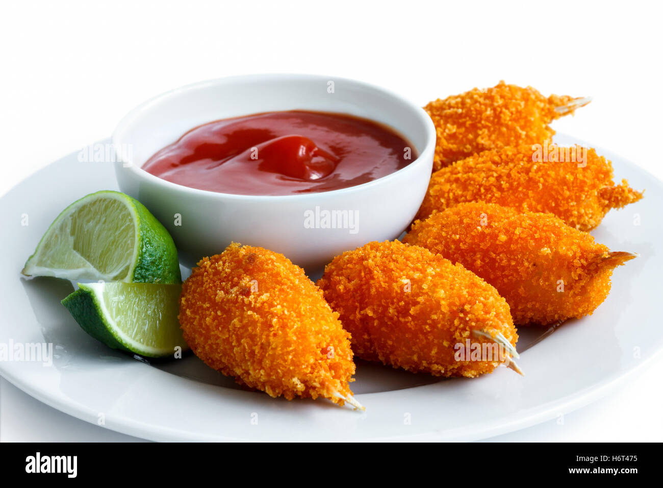 Assiette de pinces de crabe surimi pané frit avec bol de ketchup et de tranches de citron isolé sur blanc. Banque D'Images