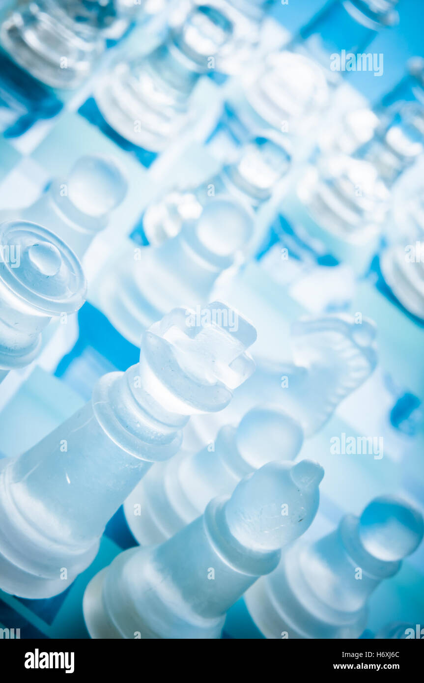 Gros plan de pièces d'échecs en verre mat et transparent sur un échiquier en verre bleu, vu de dessus sous un angle diagonal Banque D'Images