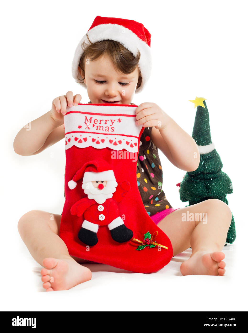 Trois ans petite fille à la recherche d'un cadeau de Noël dans une chaussette rouge Banque D'Images