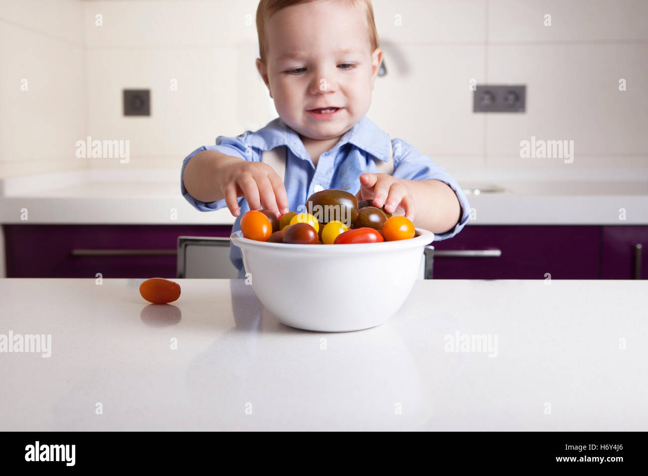Bébé Garçon jouant avec tomates cerises colorées. L'éducation sur la nutrition saine pour les enfants concept Banque D'Images