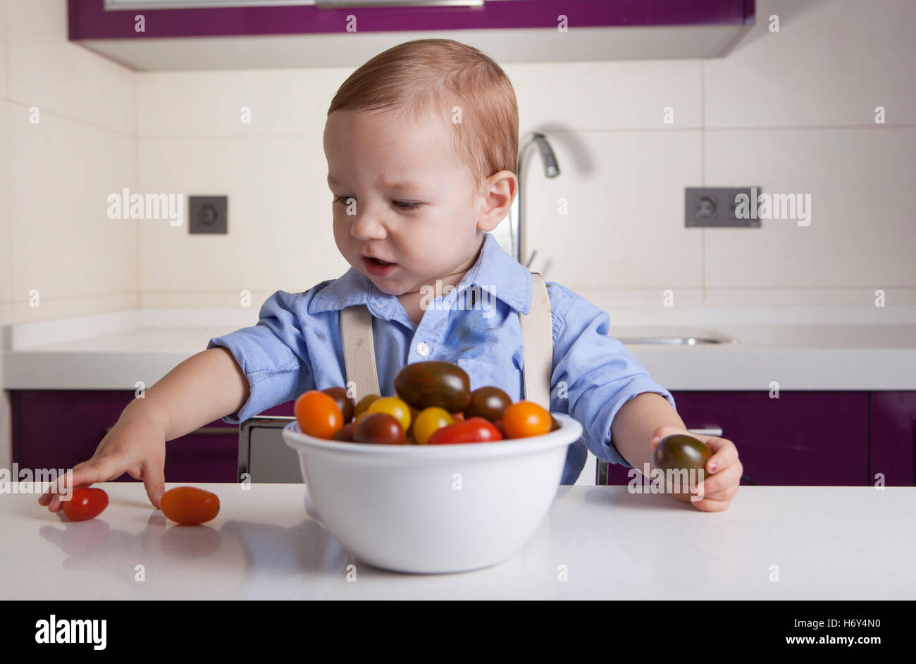 Bébé Garçon jouant avec tomates cerises colorées. L'éducation sur la nutrition saine pour les enfants concept Banque D'Images