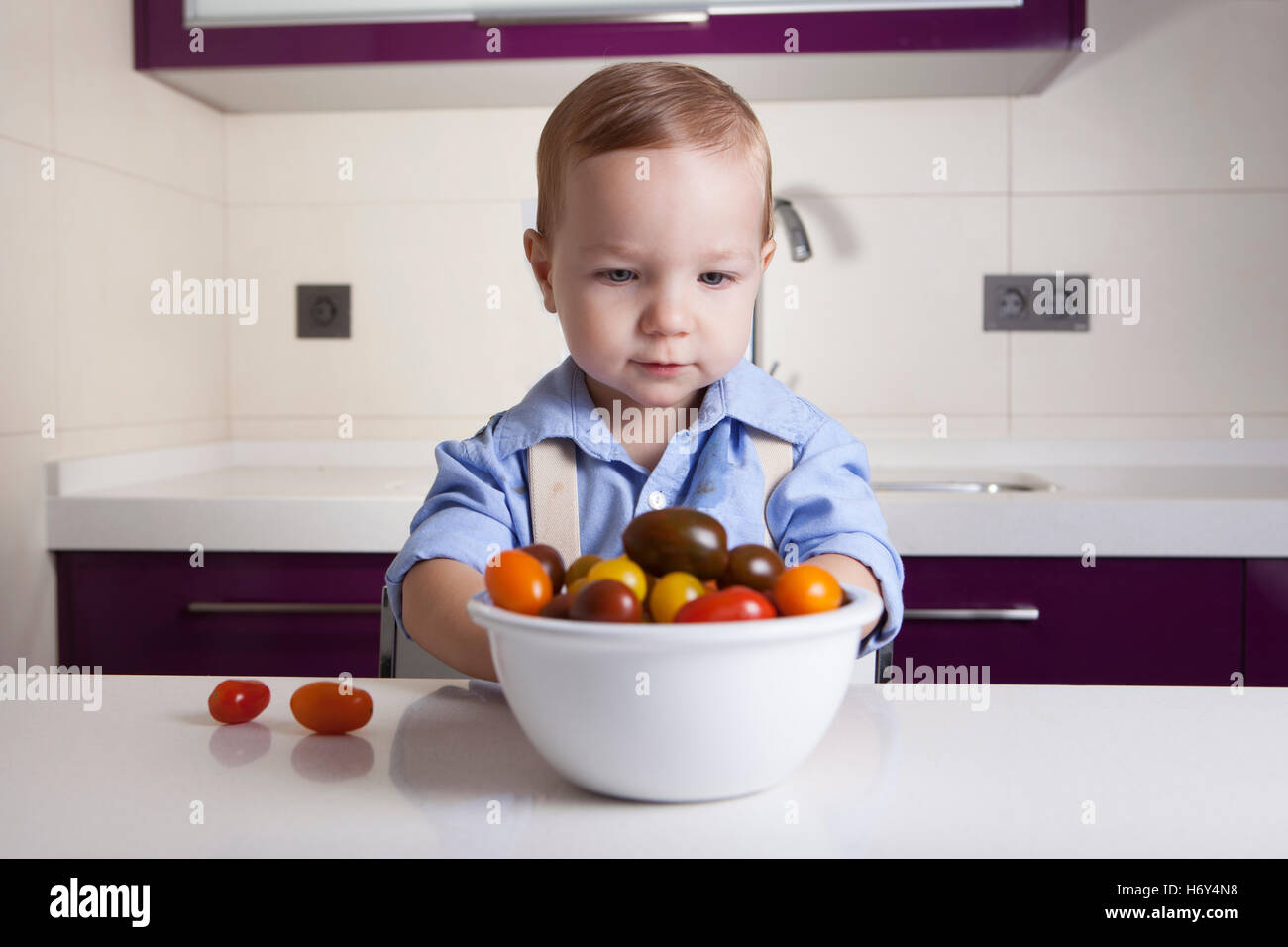 Bébé Garçon jouant avec tomates cerises colorées. L'éducation sur la nutrition saine pour les enfants concept Banque D'Images