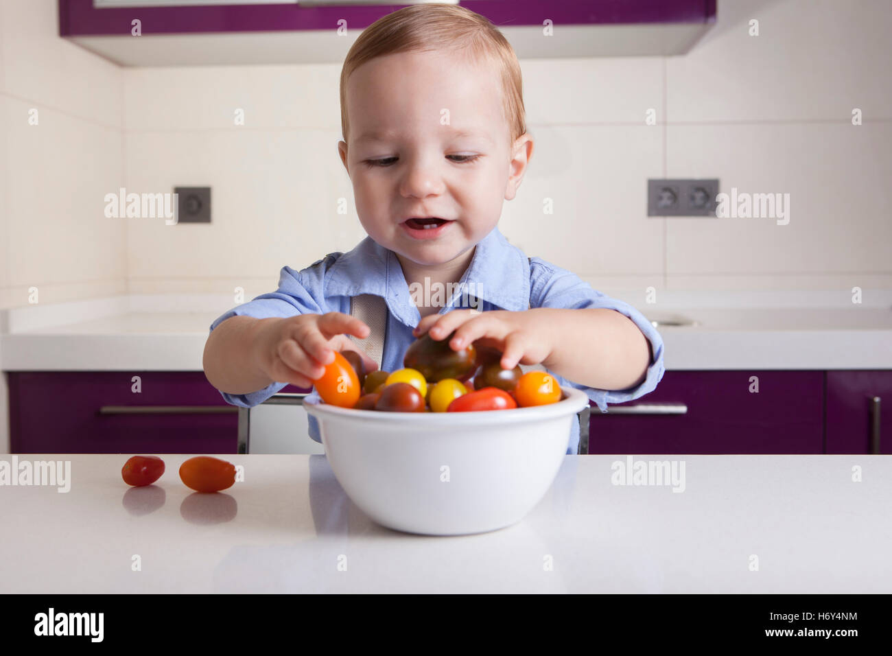 Bébé Garçon jouant avec tomates cerises colorées. L'éducation sur la nutrition saine pour les enfants concept Banque D'Images
