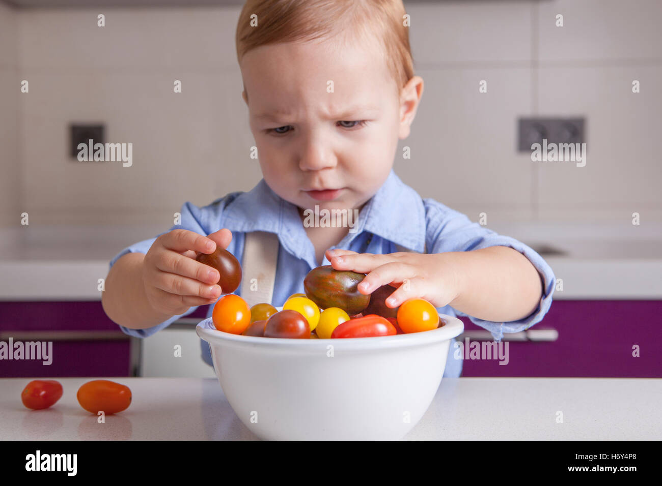 Bébé Garçon jouant avec tomates cerises colorées. L'éducation sur la nutrition saine pour les enfants concept Banque D'Images