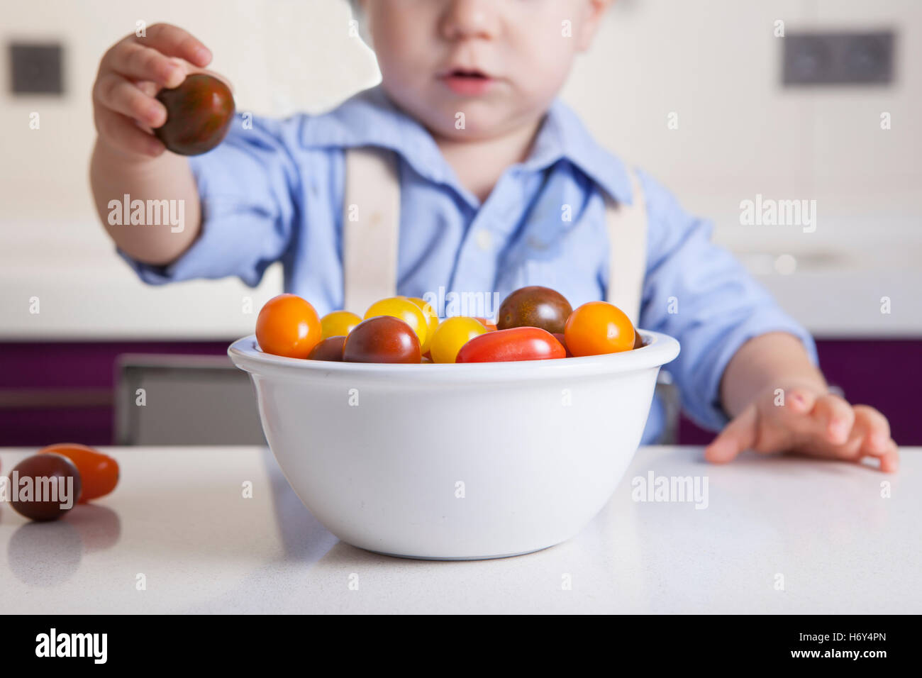 Bébé Garçon jouant avec tomates cerises colorées. L'éducation sur la nutrition saine pour les enfants concept Banque D'Images