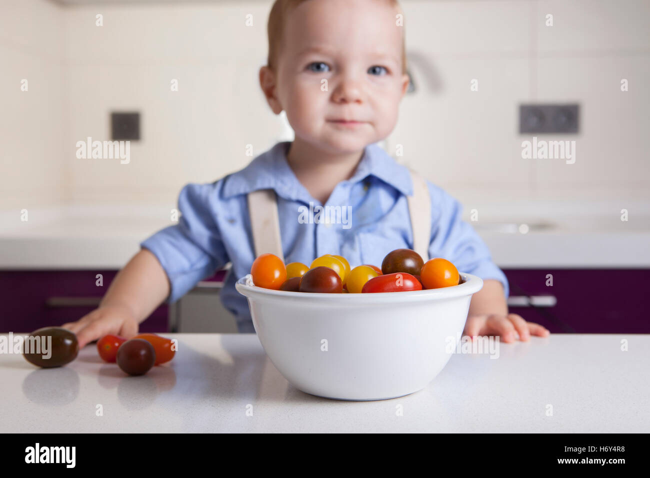 Bébé Garçon jouant avec tomates cerises colorées. L'éducation sur la nutrition saine pour les enfants concept Banque D'Images