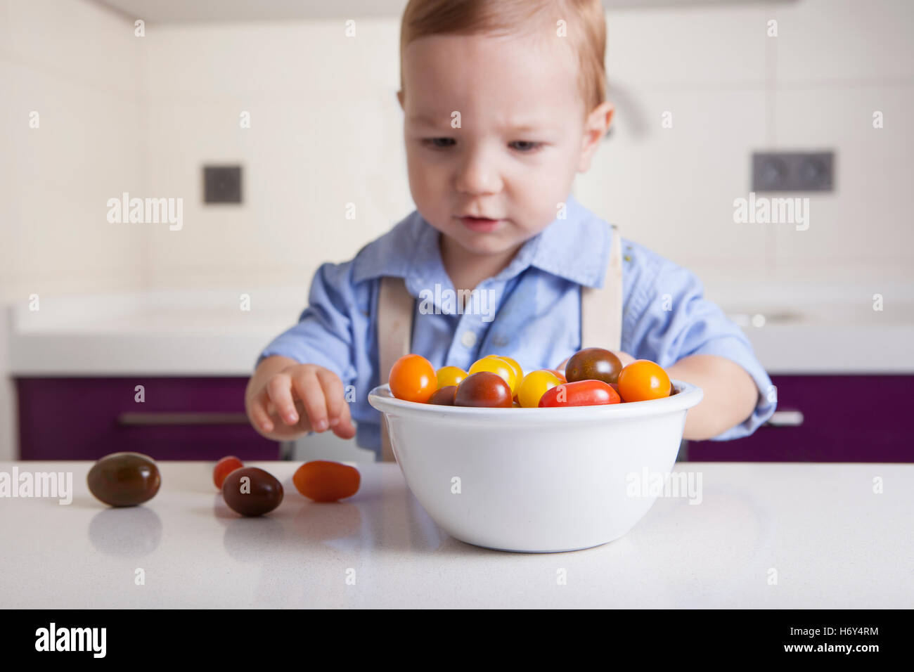 Bébé Garçon jouant avec tomates cerises colorées. L'éducation sur la nutrition saine pour les enfants concept Banque D'Images