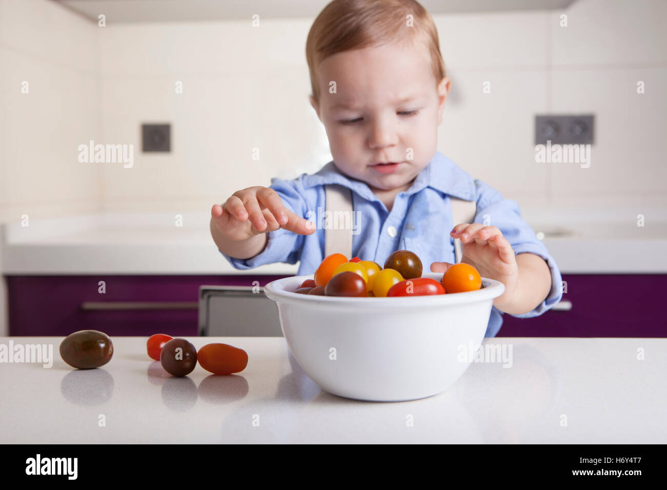 Bébé Garçon jouant avec tomates cerises colorées. L'éducation sur la nutrition saine pour les enfants concept Banque D'Images