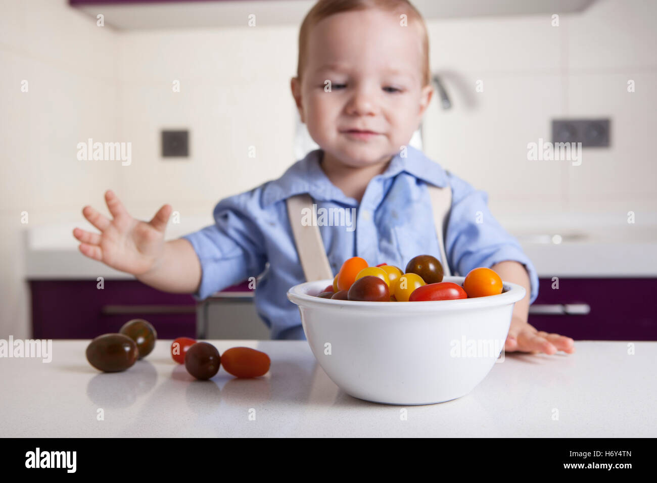 Bébé Garçon jouant avec tomates cerises colorées. L'éducation sur la nutrition saine pour les enfants concept Banque D'Images