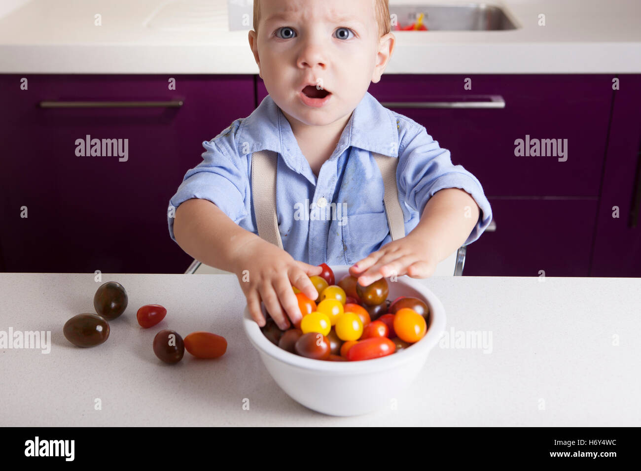Bébé Garçon jouant avec tomates cerises colorées. L'éducation sur la nutrition saine pour les enfants concept Banque D'Images