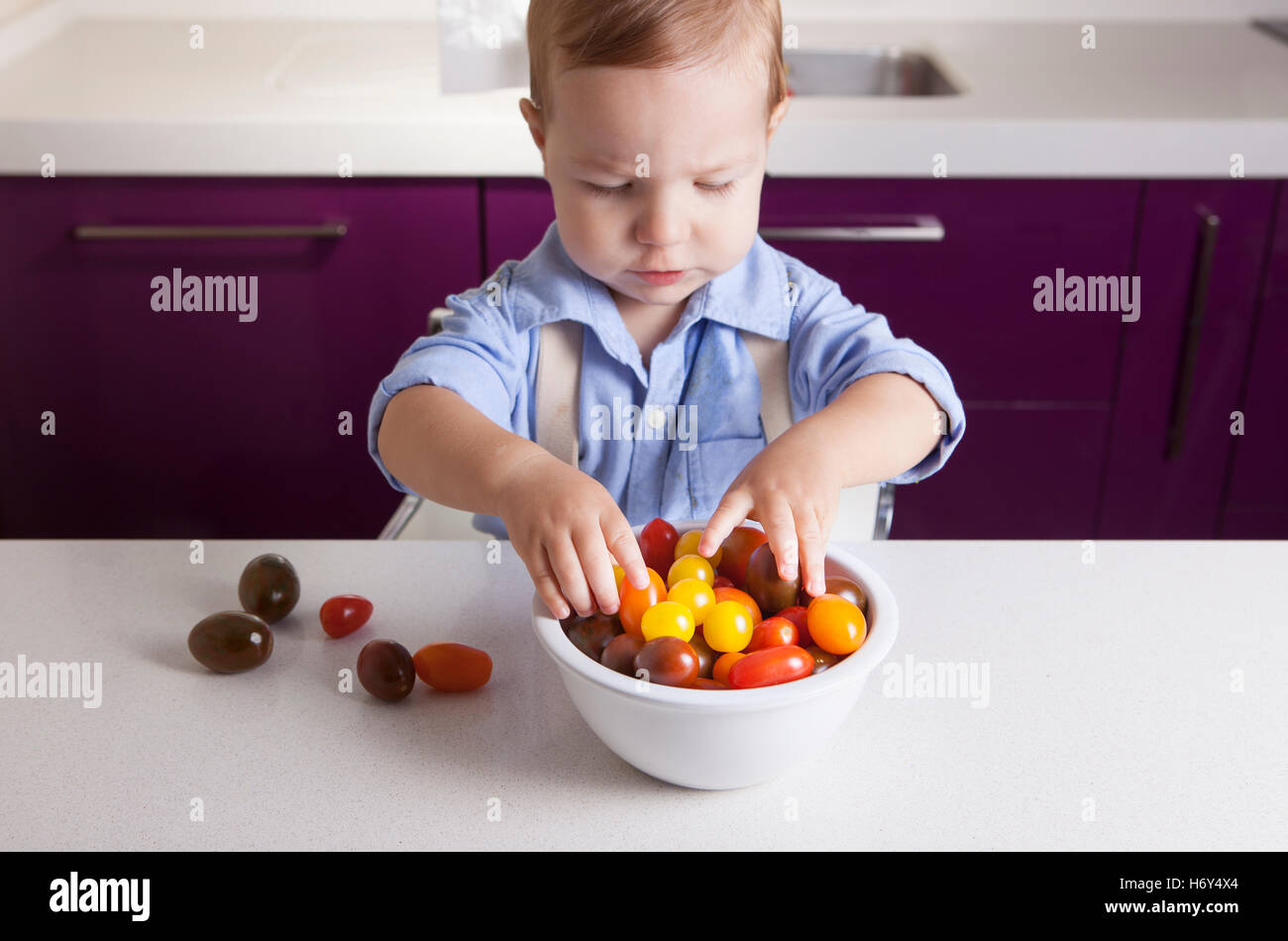 Bébé Garçon jouant avec tomates cerises colorées. L'éducation sur la nutrition saine pour les enfants concept Banque D'Images