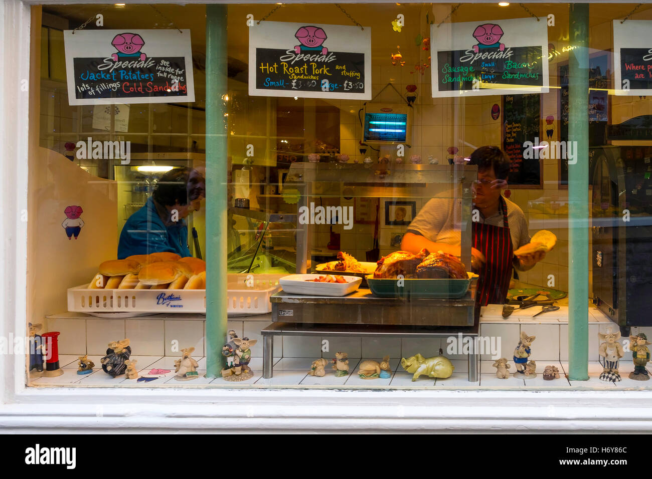 Les joints fraîchement rôtis de viande de porc et saucisses dans une vitrine de la vente de sandwichs chauds. Banque D'Images