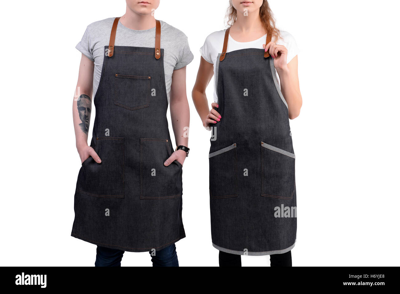 Jeunes chefs ou maîtres d'homme et de la femme pose, portant des tabliers isolé sur fond blanc. Banque D'Images