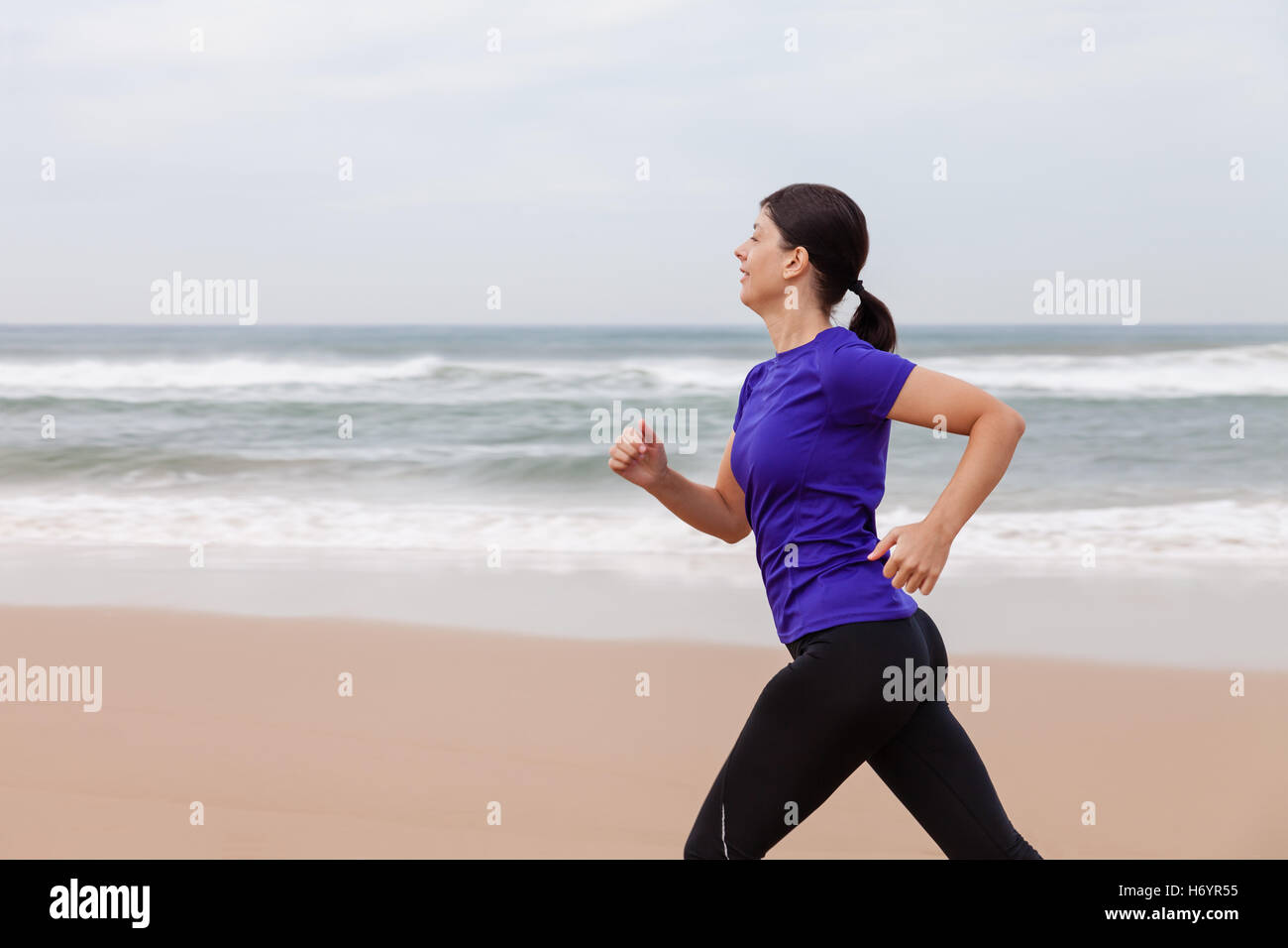 Athlète féminin tournant à la plage une journée d'automne. Banque D'Images