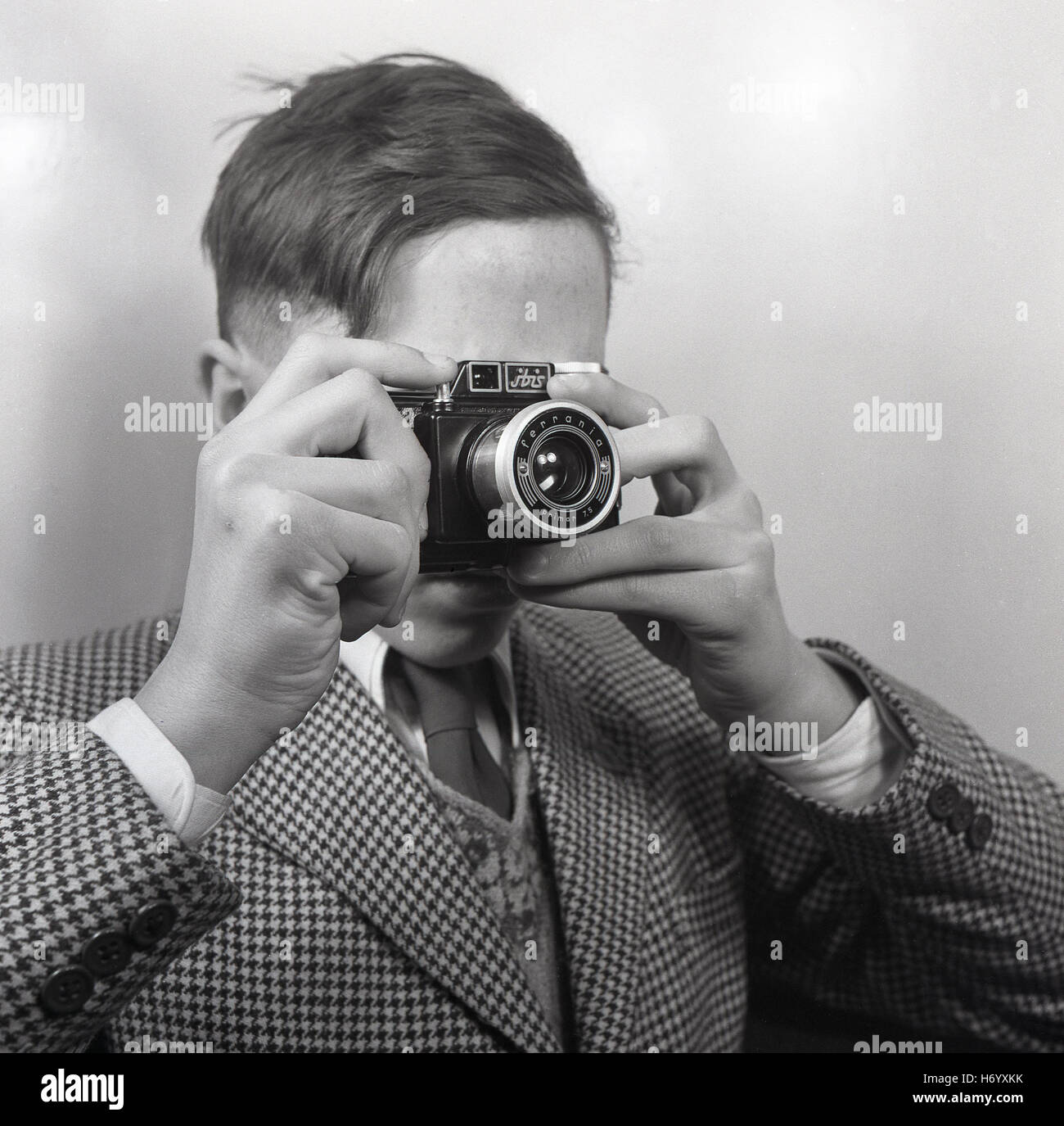 Années 1950, historique, Angleterre, Royaume-Uni, jeune homme portant une veste de vérifier à l'aide, en tenant d'une photo avec un appareil-photo de film italien fait un viseur, Ferrania Primar ibis 75. Banque D'Images