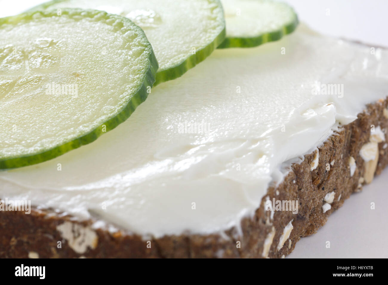 Concombre émincé sur propagation épais fromage à la crème sur pain santé sombre. Banque D'Images