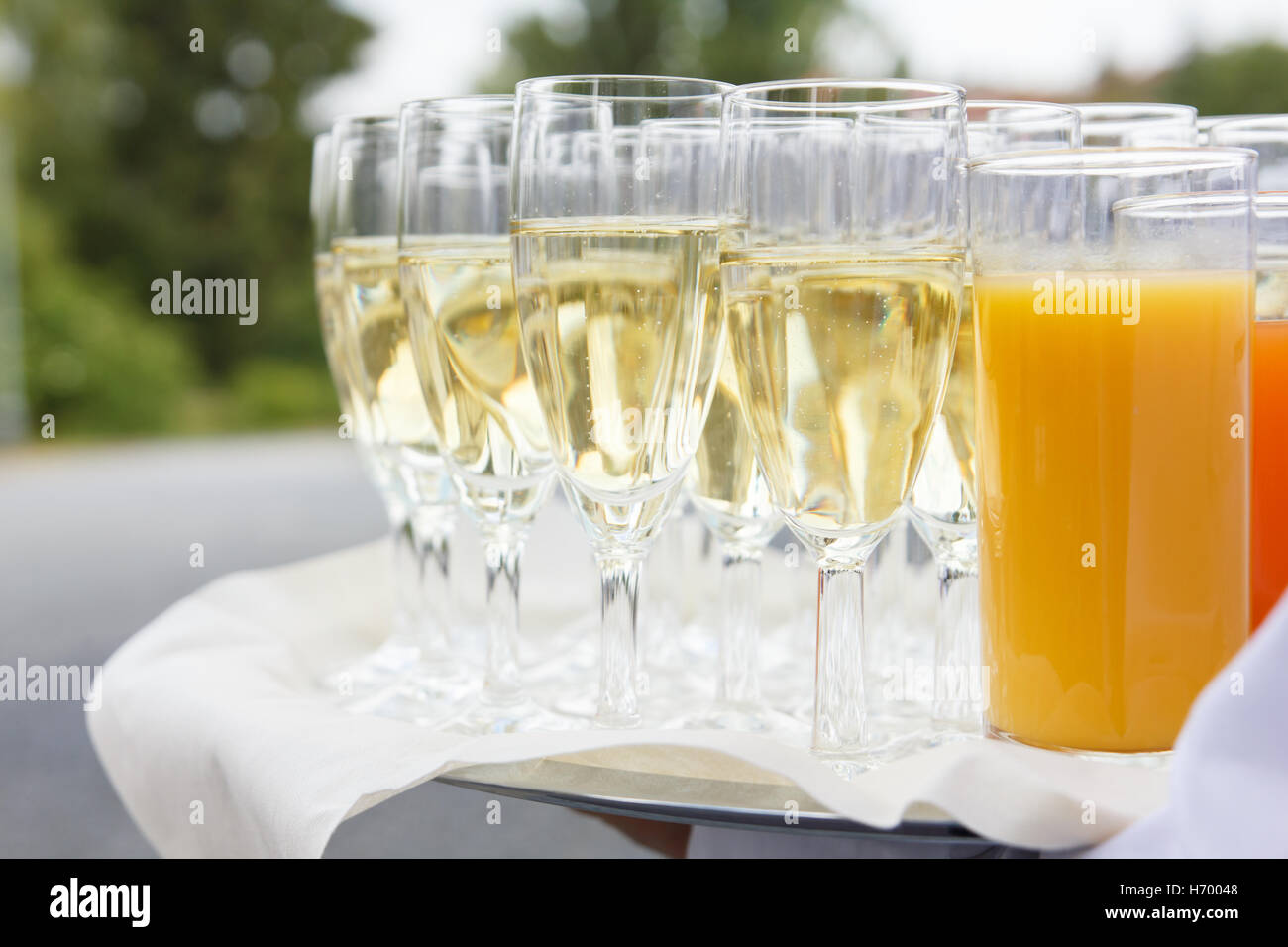 Détail d'un waiter holding un plateau de champagne et autres boissons. Des problèmes de mise au point arrière-plan vert. Banque D'Images