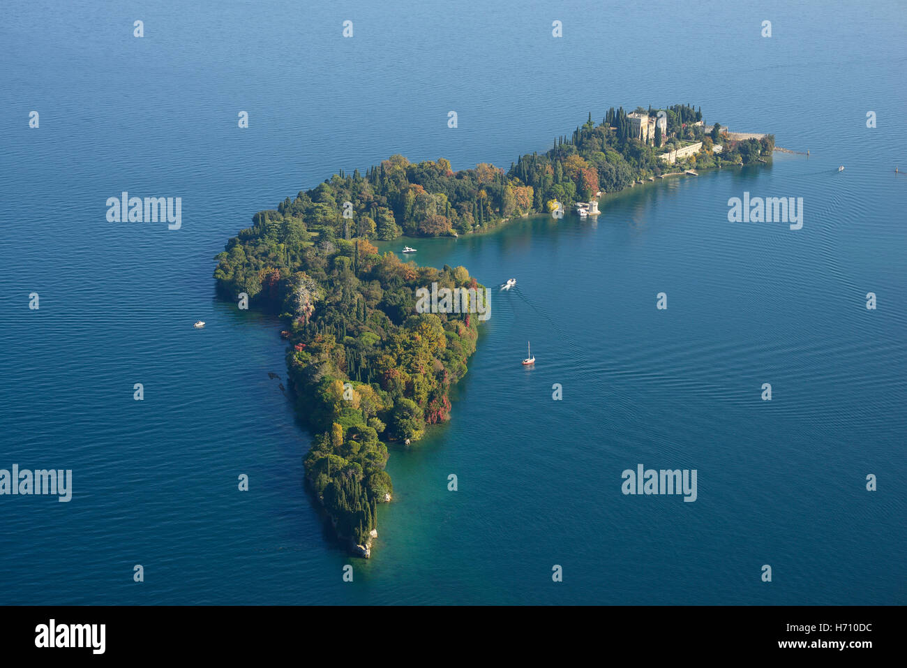 VUE AÉRIENNE. Île boisée à l'automne et une villa néo-gothique vénitienne. Isola del Garda, Lac de Garde, province de Brescia, Lombardie, Italie. Banque D'Images