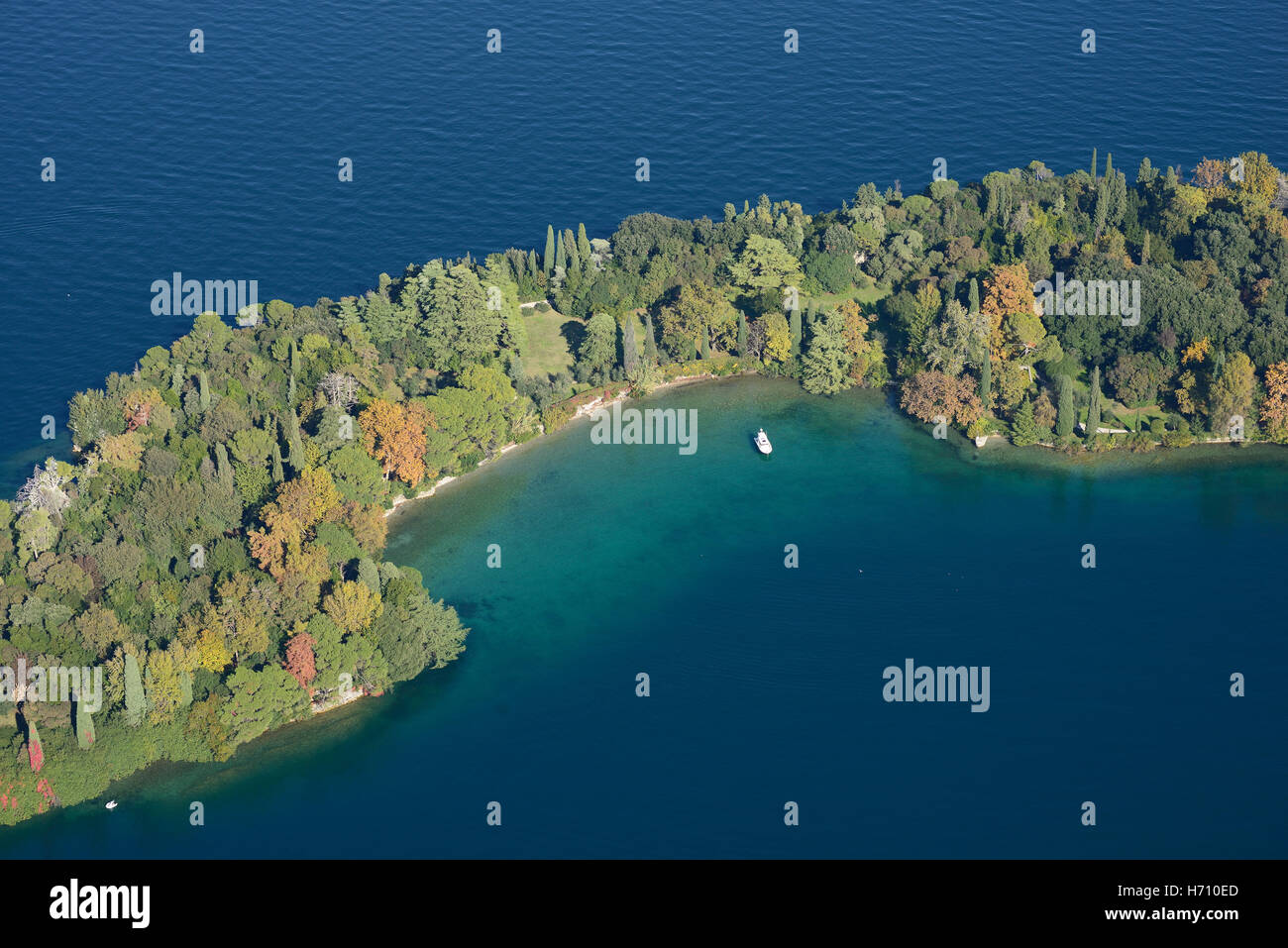 VUE AÉRIENNE. Petite baie dans une île boisée à l'automne. Isola del Garda, Lac de Garde, province de Brescia, Lombardie, Italie. Banque D'Images