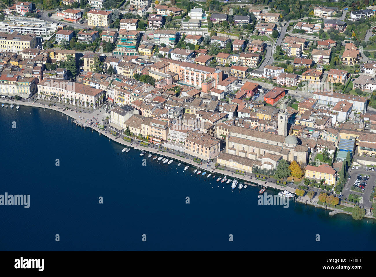 VUE AÉRIENNE. Ville pittoresque avec sa rangée de bateaux sur le bord du lac de Garde. Salò, province de Brescia, Lombardie, Italie. Banque D'Images