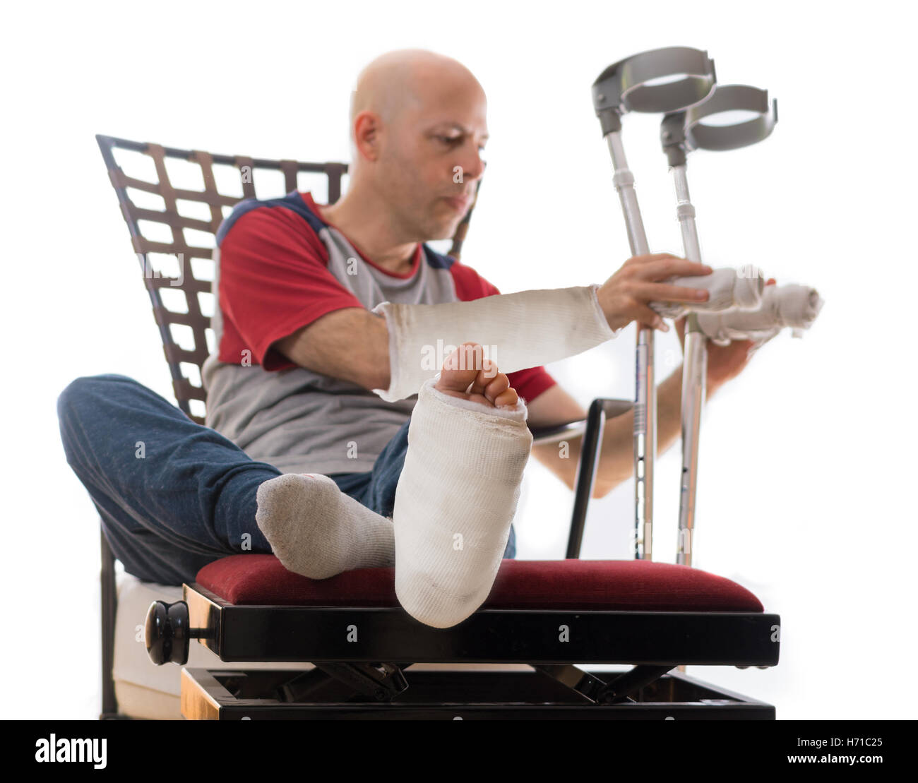 Jeune homme après un grave accident avec fracture de la cheville et du poignet et le plâtre blanc et plâtres en fibre à la jambe et le bras, mettant n Banque D'Images