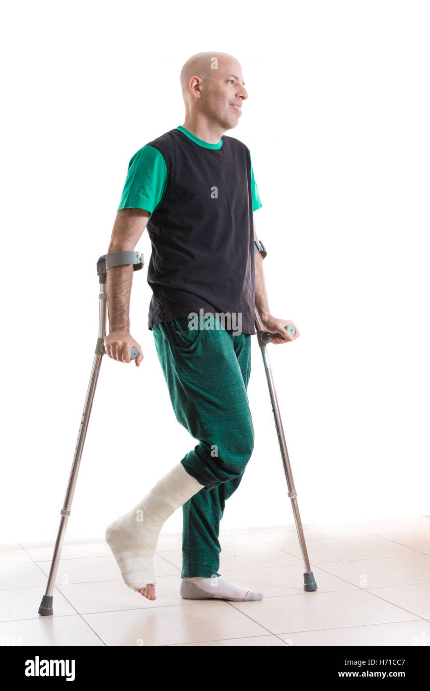 Jeune homme avec une cheville cassée et une fibre de verre et en plâtre à la jambe, appuyé sur ses béquilles (isolé sur blanc, plein d'adm. Banque D'Images