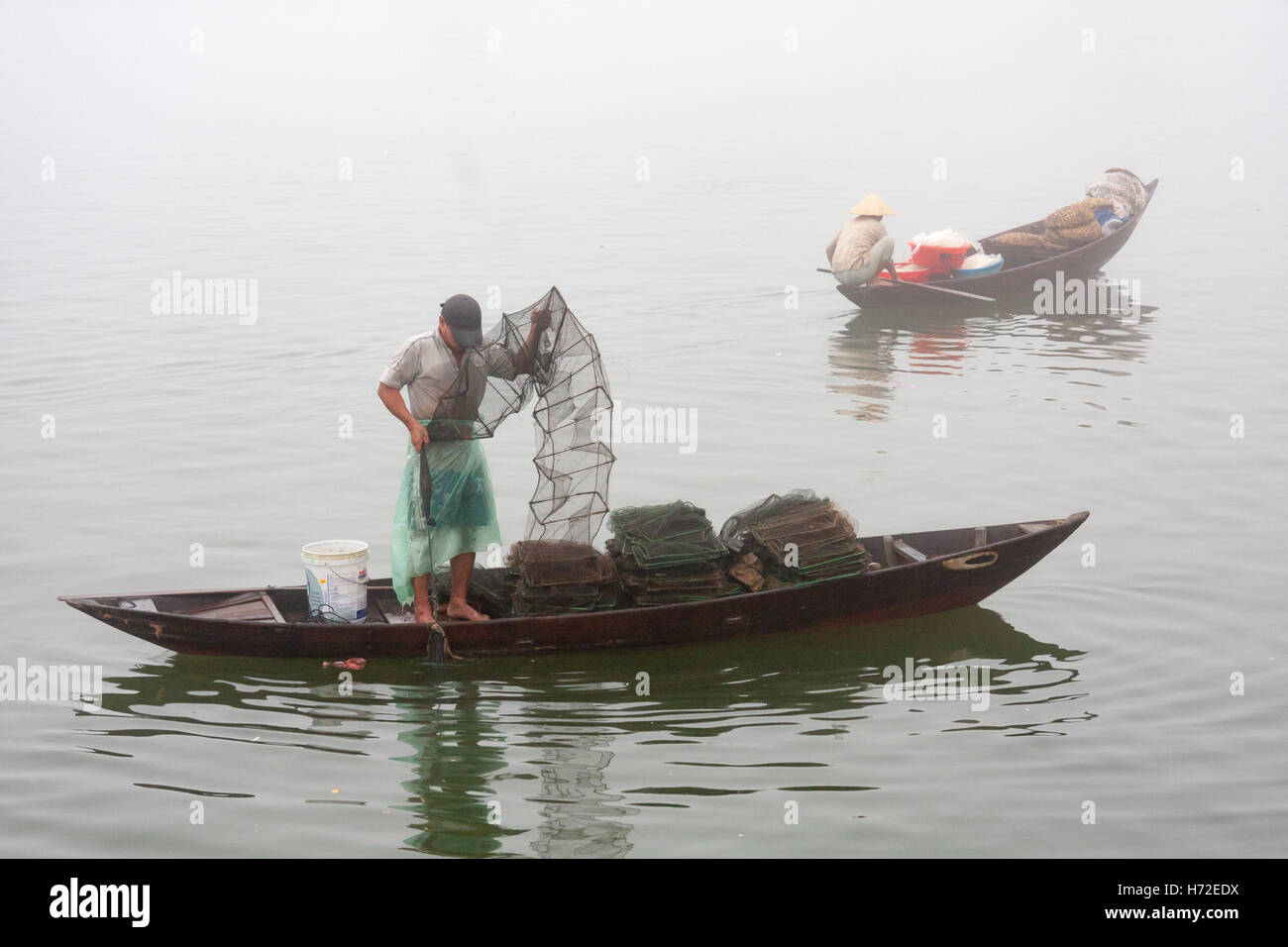 Un pêcheur vérifie ses filets sur un matin brumeux sur la rivière Hoi An, Vietnam Banque D'Images
