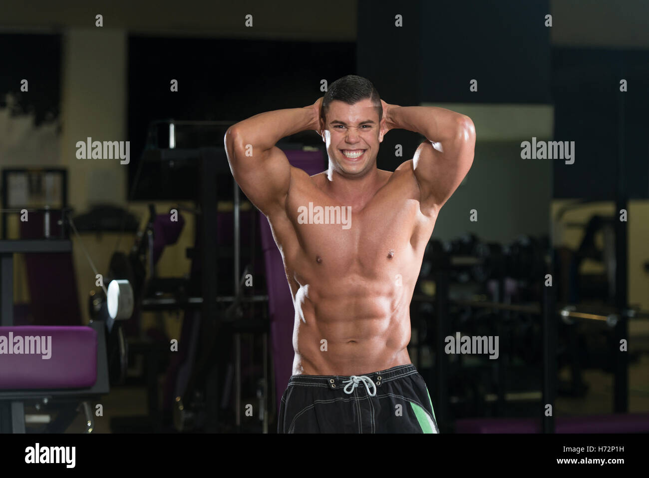Jeune homme debout forte dans la salle de sport et Flexing Muscles - Remise en forme musculaire Bodybuilder Athletic Model Posing montrant après Abs Banque D'Images