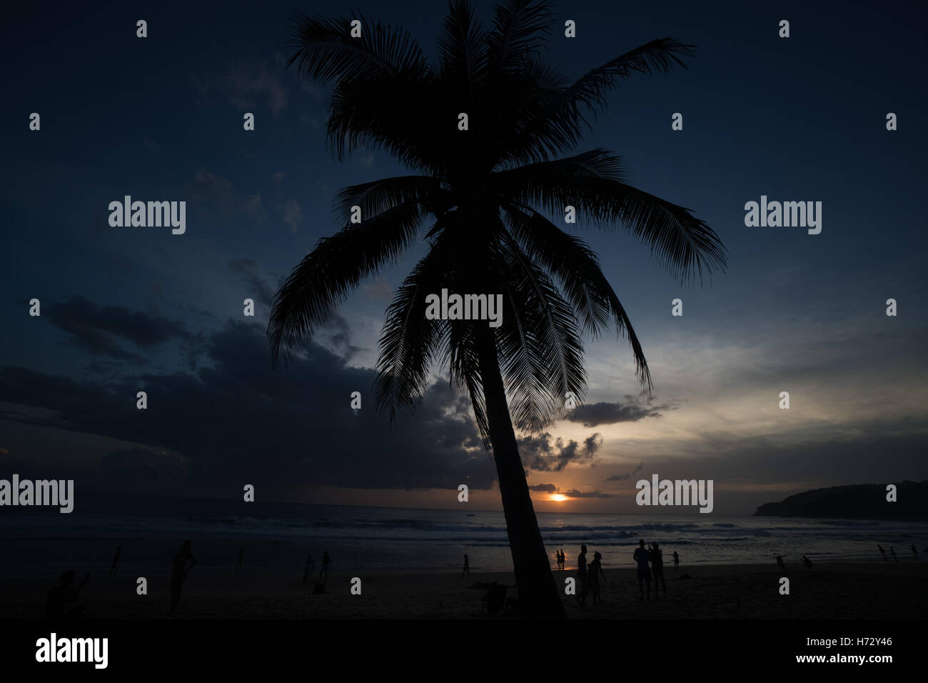 Palmier et des silhouettes de gens qui marchent sur la plage pendant le coucher du soleil magnifique. Concept d'été Banque D'Images