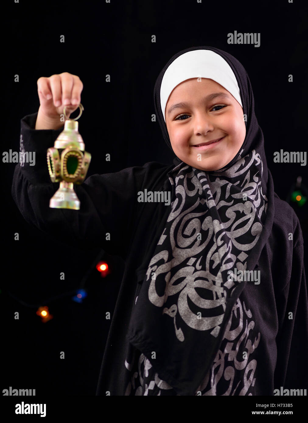 Heureux jeune musulmane avec lanterne sur le Ramadan nuit lumières fond flou artistique Banque D'Images